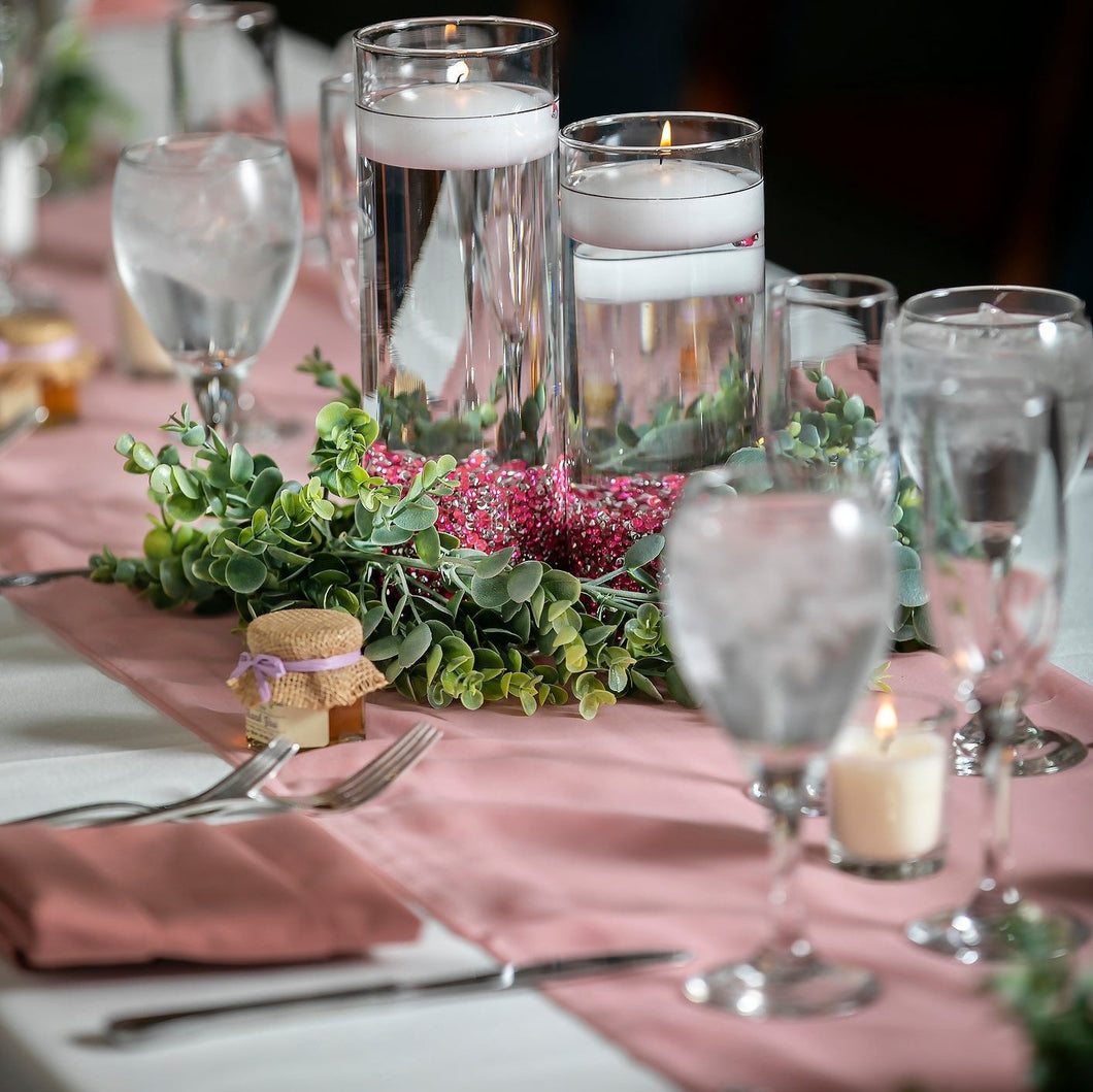 Wedding table runner with drinking glasses and glass candle centerpieces