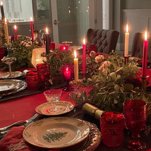 Holiday red Christmas tableclotjh, fine china and candls on this lovely tablescape.