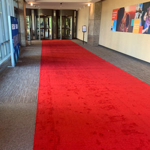 Plush red carpet aisle runner at the entrnce to a special event