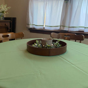 Home linens in sage on a round table by a window