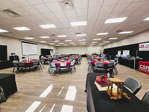 Conference room with tables, blank tablecloths, chairs, and a projector screen.
