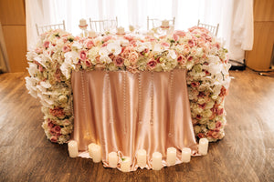 Duchess linens on a reception head table with a large flower bouquet presentation