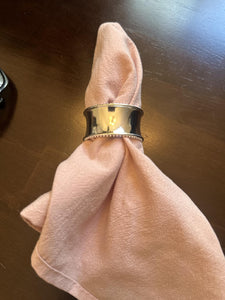 Napkin ring on a folded pink napkin on a wooden surface