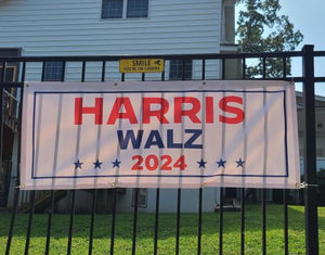 Harris Walz outdoor banner hanging on a fence