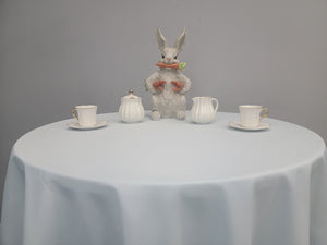 Fine poly linens on a round table with an Easter statuette on top