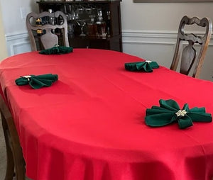 Red oval tablecloth with hunter green napkins during Christmas