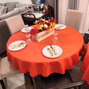 Poly Round tablecloths in orange in home living room setting with plates and cutlery