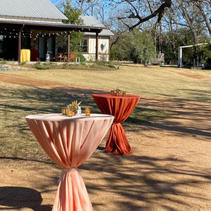 Fine linens on two outdoor cocktail tables during a wedding reception