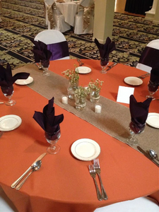 Burnt Orange wedding linens with a burlap table runner during a wedding with black napkins
