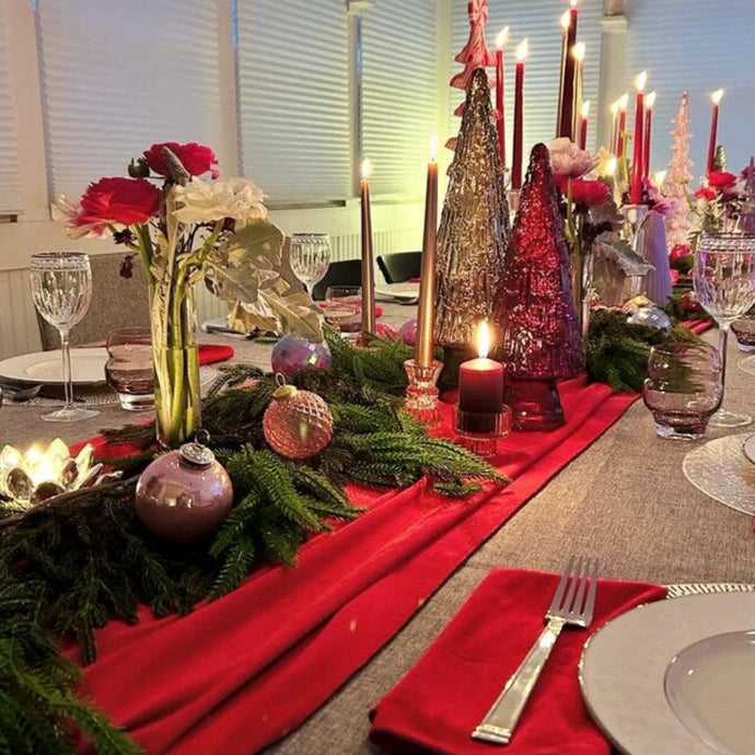 Decorative Christmas table cloth and red velvet napkins  with candles, flowers and holiday decorations.