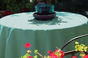 Grand-style tablecloth in white on a round outdoor table with flowers