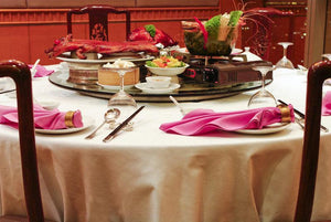 Corporate table linens on a round Chinese restaurant table with pink napkins and a cooked pig on top