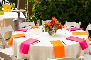 Plush tablecloth on an outdoor round table with multi colored napkins and flowers