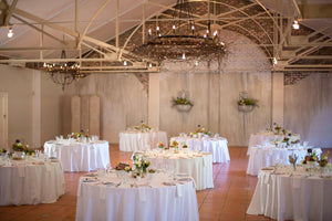 Barn-style wedding tables with white table linens and matching napkins