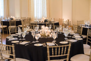 Black Poly Premier table linens at a wedding reception with gold banquet chairs