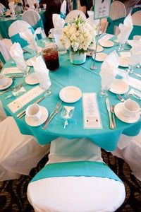 Wedding reception table with blue linens and chair sashes