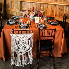 Square burnt orange tablecloth on banquet table with elegant event decor and Premier Table Linens touch.