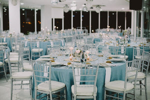 Round table linens beautifully draped over tables at a catering hall reception with white napkins