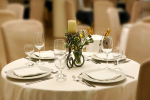 Spun poly ivory-colored napkins on plates with a center candle