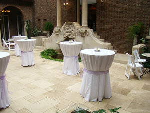 White linens on cocktail cover tables with ties in the center and candles on top