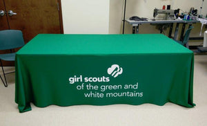 A fitted table throw in green with white letters and logo for the Girl Scouts