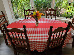 red white check tablecloth on an oval table with vase of flowers