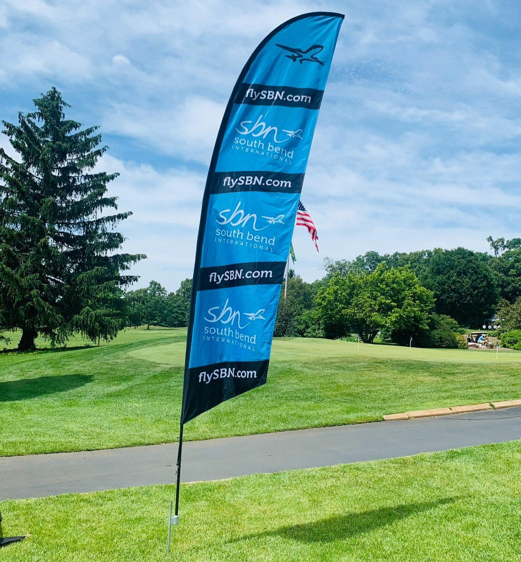 Custom-printed 6-foot feather flag with a ground stake at a golf course event