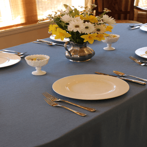 Blue oval tablecloth with china and a vase of flowers 