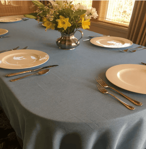 Blue oval tablecloth with a vase of flowers on the table