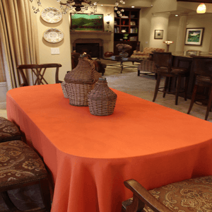 Orange oval tablecloth on a large dining room table at a home
