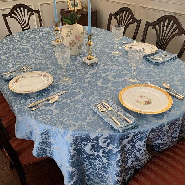 Miranda Damask Oblue damask oval tablecloth with ceramic vase and candles.