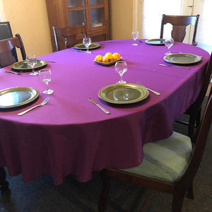 Purple oval tablecloth with china and glasses on the table