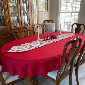 Red oval tablecloth with a table runner and candles