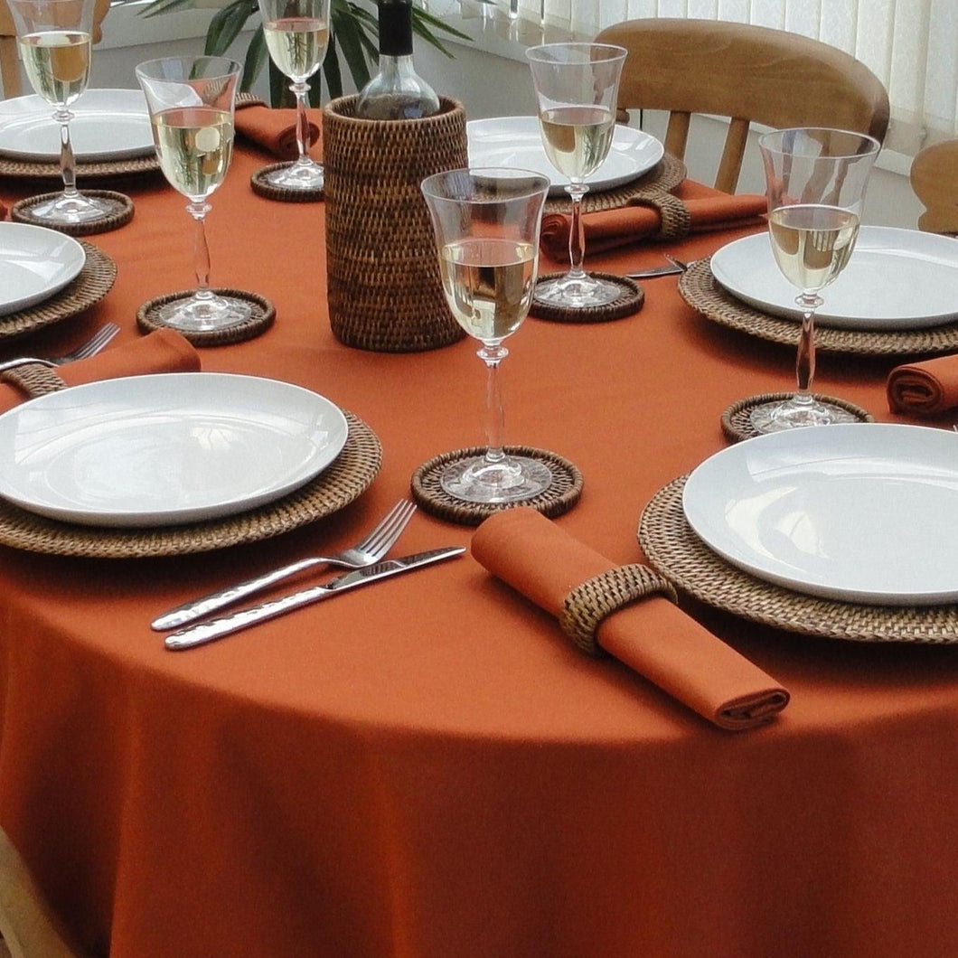 Burnt orange oval tablecloth with dishes and wine glasses