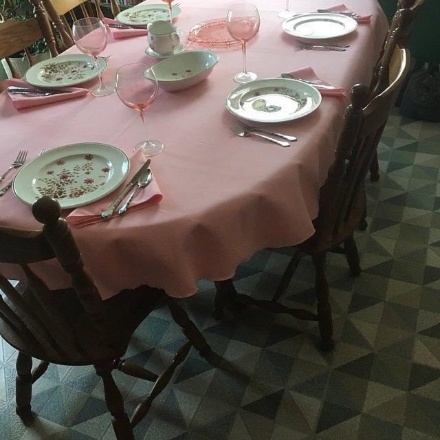 Pink oval tablecloth with beautiful china and place settings