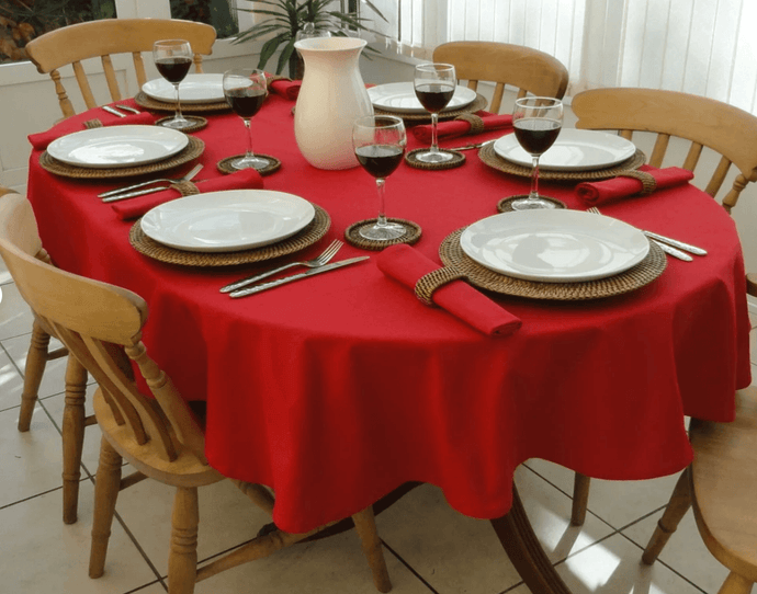 red table linen on a oval table with wine glasses and china