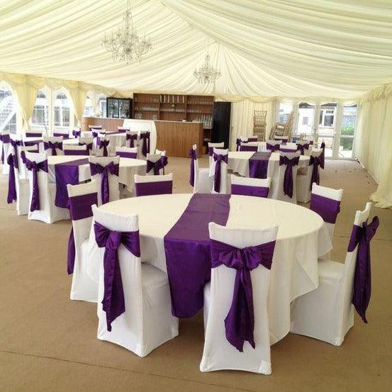 Purple Poly chair sashes and table runners on round white tables