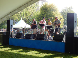 Custom blue stage skirt on an outdoor stage with performers and musical equipment