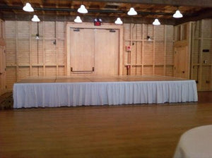 a white skirt on a small stage in an indoor dancehall 