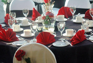 Round black tablrcloth with red napkins formal table setting