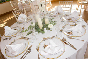 White wedding tablecloth with gold plated dishes and candles 