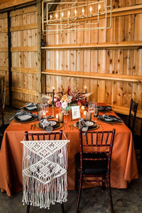 Burnt Orange colored table cloth on a wedding reception table in a bohemian style setting