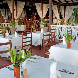 White linens on square tables in a tropical outdoor restaurant setting with matching napkins