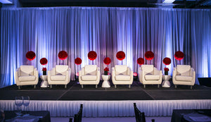 White stage skirts with box pleats during an elegant interview setup with soft backlighting