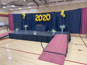 a plum colored stage skirt in a school gym for a graduation ceremony with flowers and balloons