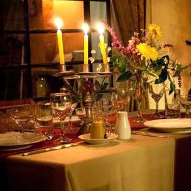 Havana linens on a rectangular table with plates, glasses, flowers, and lit candelabra