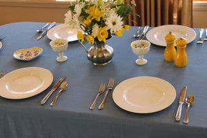Slate blue colored tablecloth at an Easter celebration with plates, flowers, and mini easter eggs