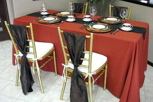 Formal table linens in red with a black table runner & matching chair sashes at a wedding reception