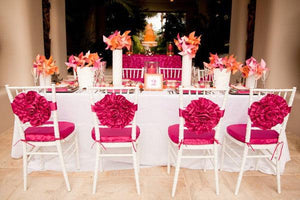 White Table cloth on a numbered table at a wedding reception with pink flower sashes on chairs
