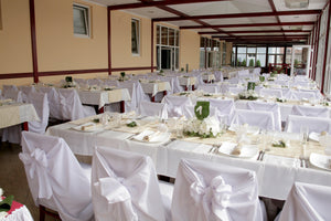 white table linens in a banquet restaurant wedding reception set up with ivory napkins and runners